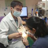 An optometrist demonstrates to a patient how to use a hand-held magnifier.
