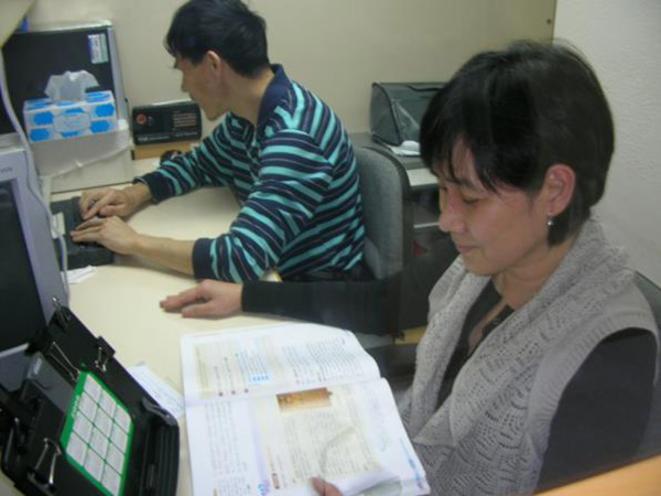 Volunteer assisting visually impaired braille production officer