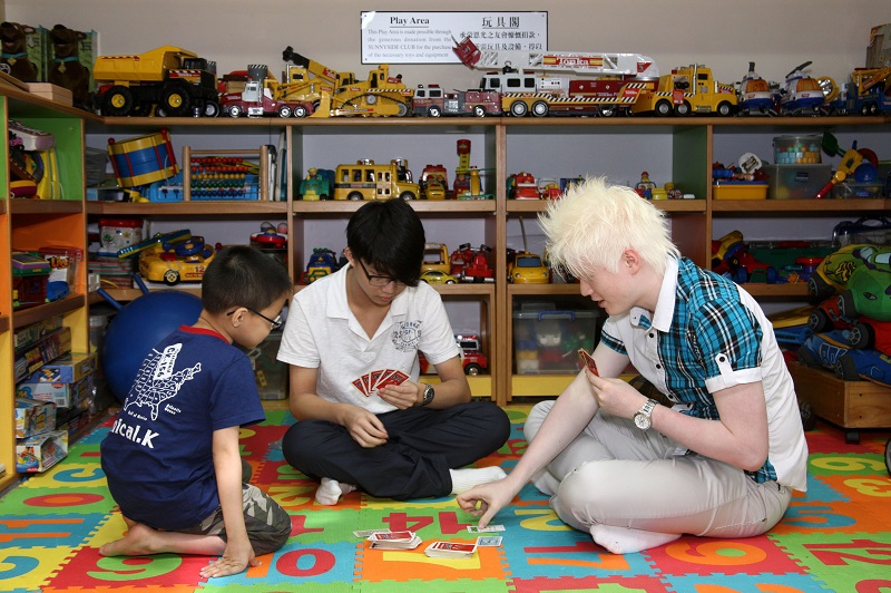 Three visually impaired youths playing board game at the Toy Corner